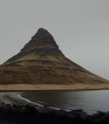 A lone mountain on the side of a lake in Iceland. 