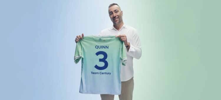 로렌초 퀸이 짙은 파란색 글씨로 “Quinn”, “3”, “Team Century”라고 적힌 녹색 및 하늘색의 팀 센츄리 유니폼을 들고 있습니다. 
