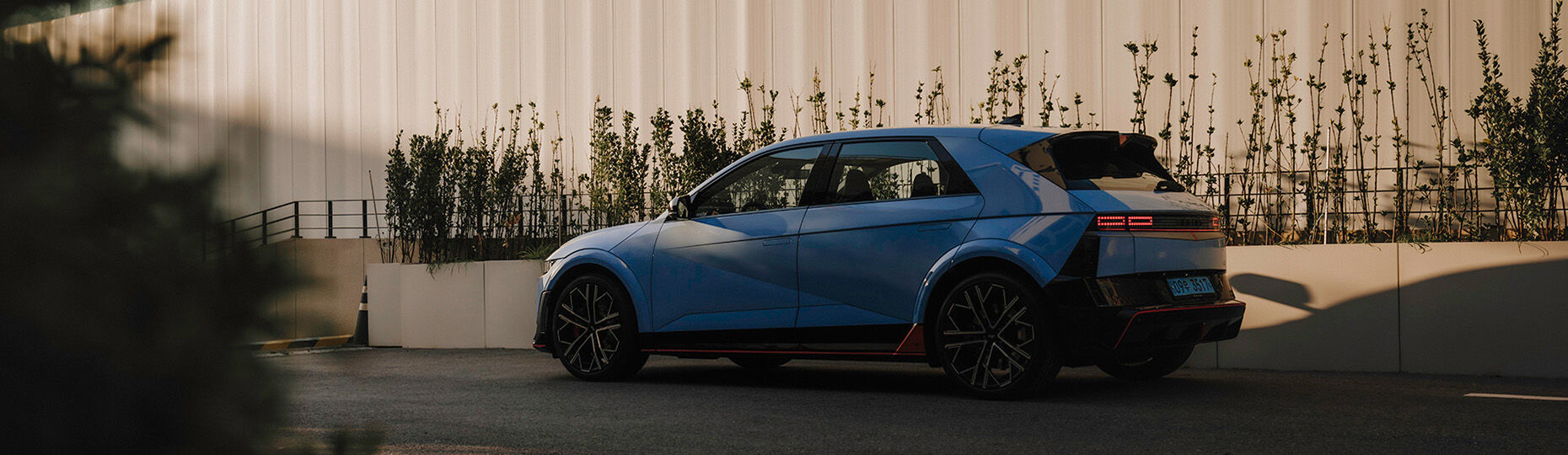 A blue car in front of wall.