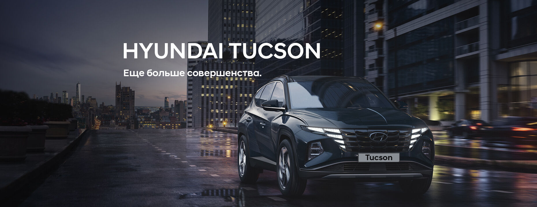 Синий Hyundai Tucson едет по дороге на фоне городских зданий