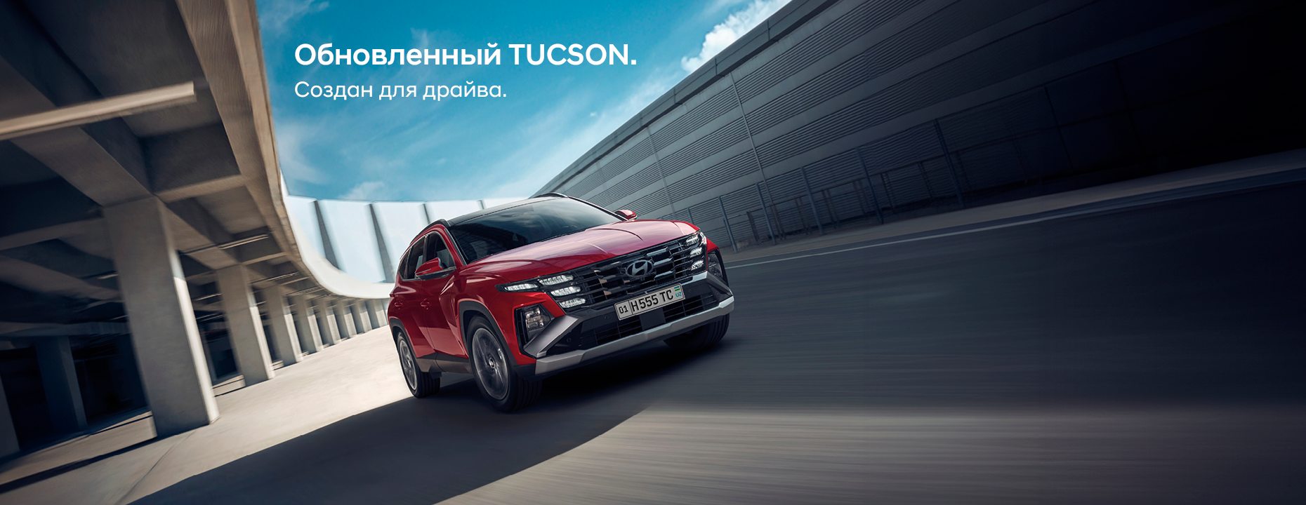 Синий Hyundai Tucson едет по дороге на фоне городских зданий