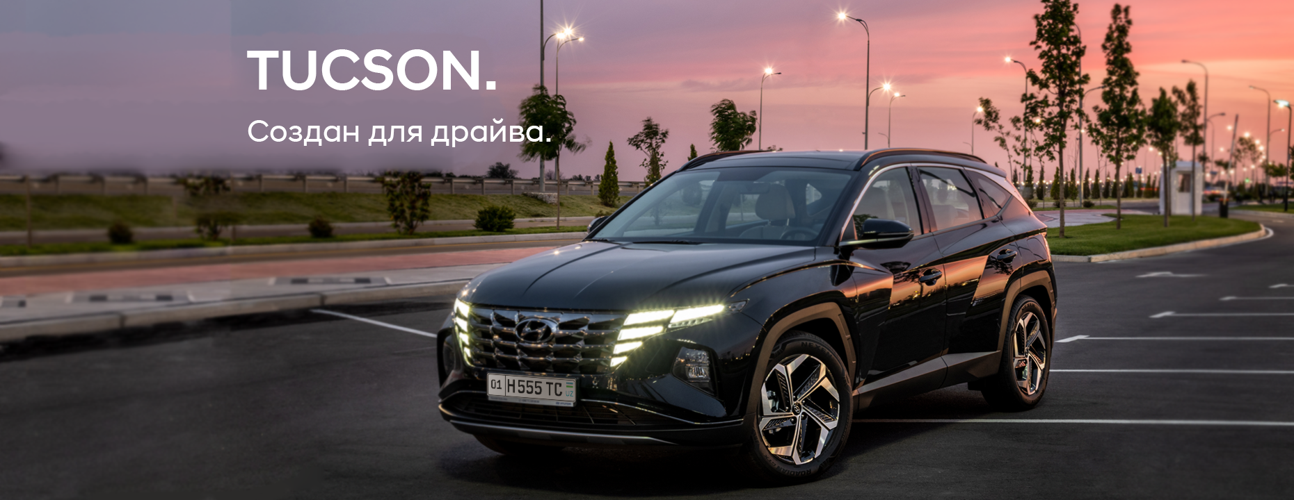 Синий Hyundai Tucson едет по дороге на фоне городских зданий