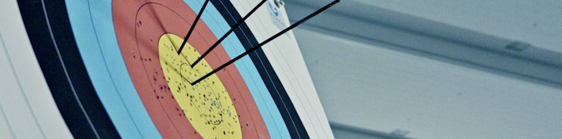 An archery target in close-up with three arrows in the bullseye circle.