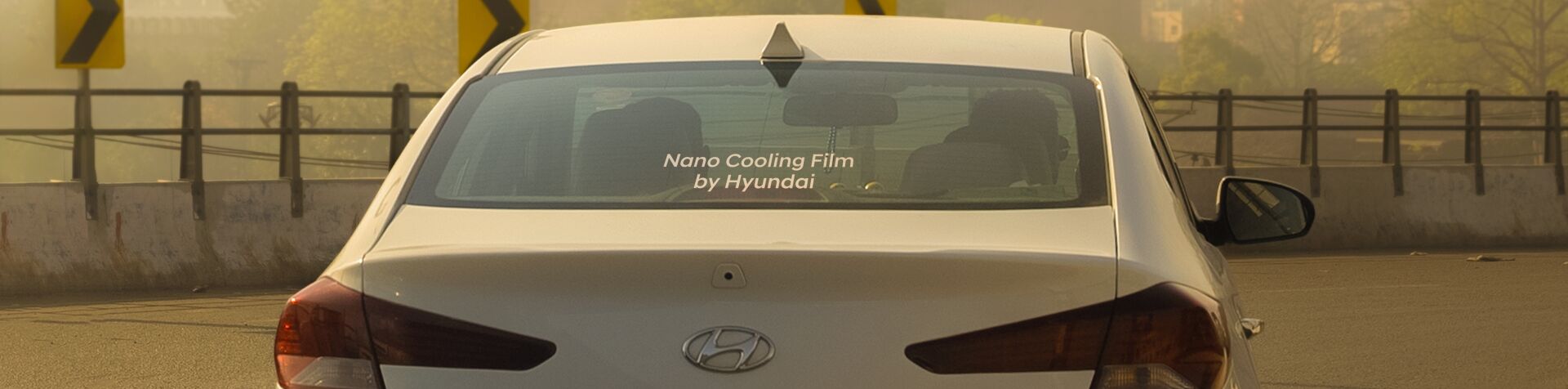 The rear view of an ELANTRA with the words “Nano Cooling Film by Hyundai” written across its back windshield