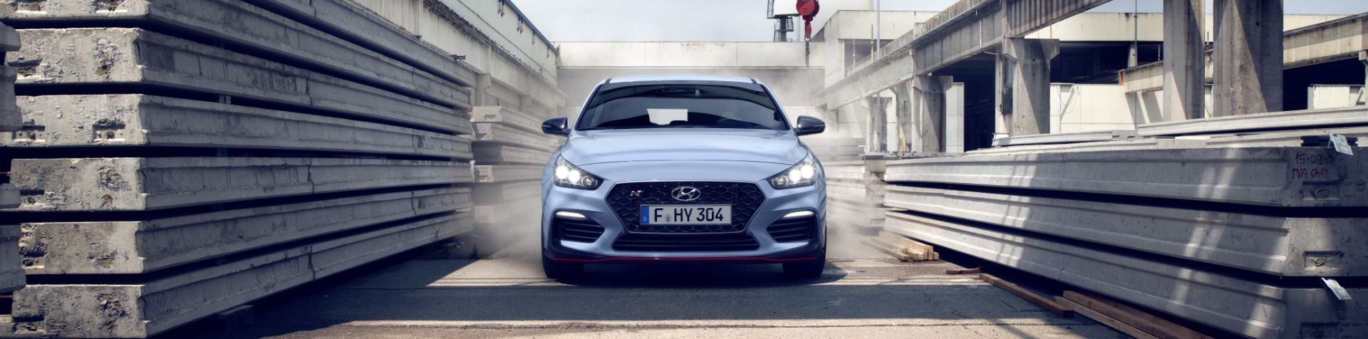 Front view of a blue Veloster N navigating around an industrial area.